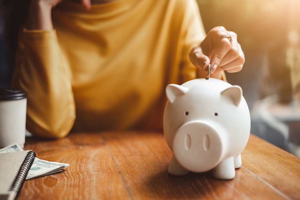 Woman hand putting a coin in a piggy bank