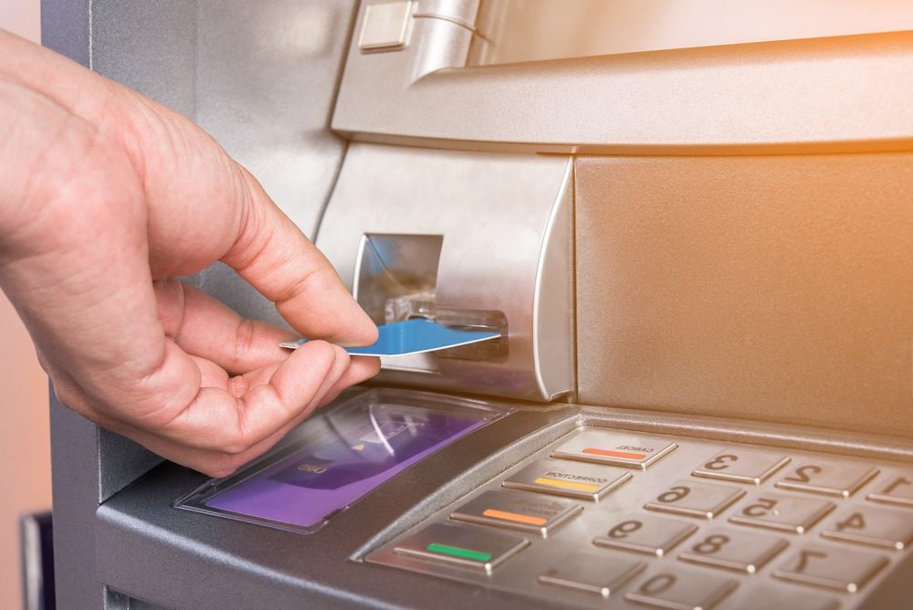 Closeup of hand inserting a bank card in an atm machine.